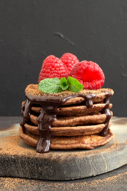 Chocolate pancakes with raspberry on a dark background.