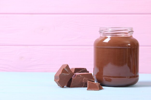 Chocolate paste in a glass jar on a colored background