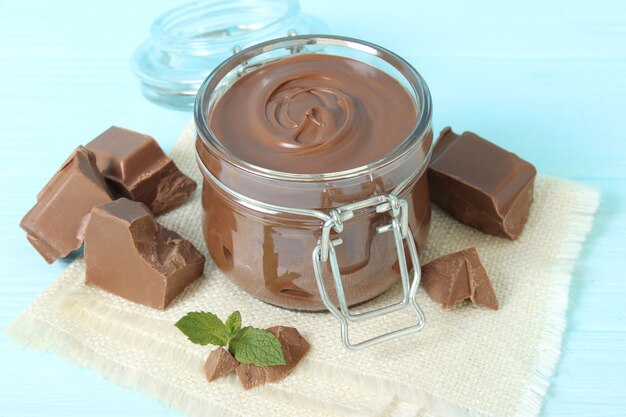 Chocolate paste in a glass jar on a colored background