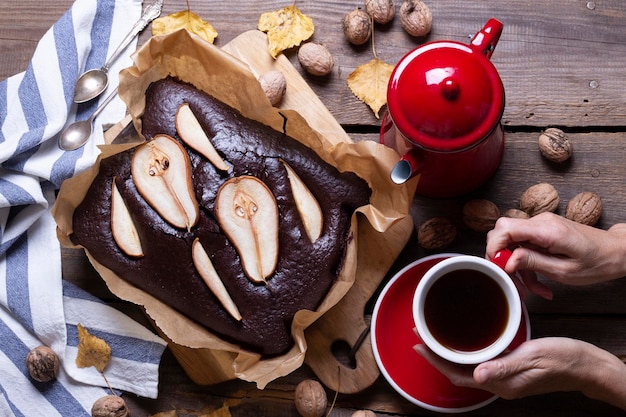 Torta al cioccolato con pere, caffettiera e tazza. natura morta e sfondo autunnale