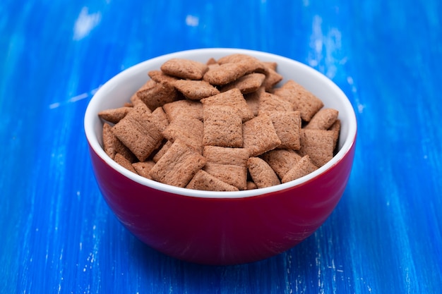 Chocolate pillows in red bowl on blue wooden