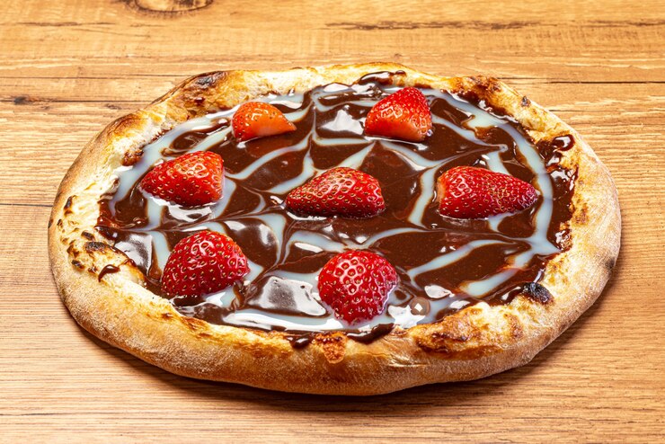 木製のテーブルにイチゴとサワークリームソースを添えたチョコレートピザ