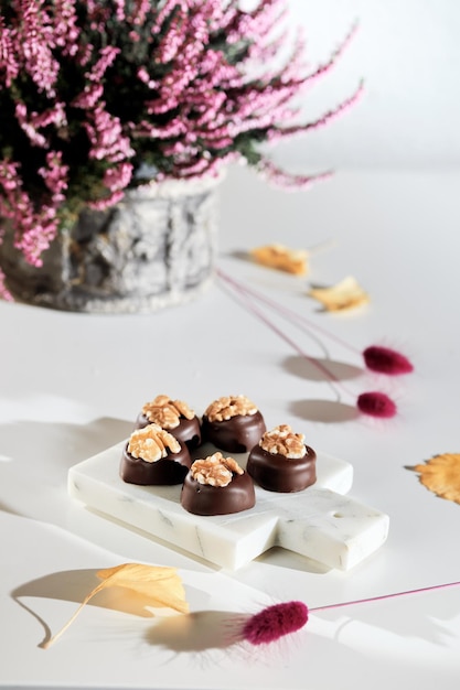 Chocolate pralines with walnut nuts on marble cutting board closeup on candy autumn arrangement