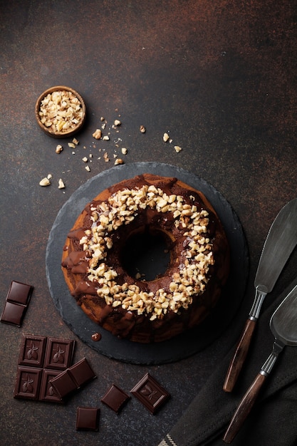 Chocolate and pumpkin bundt cake with chocolate glaze and walnut on dark concrete surface. Selective focus. Top view. Copy space