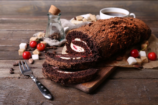 Chocolate roll with cream and berries on table close up