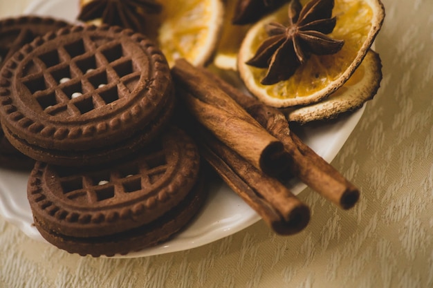 Chocolate round cookies with a layer and filling on a plate decorated with cinnamon