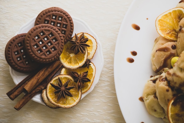 Шоколадное круглое печенье с прослойкой и начинкой на тарелке, декорированной корицей