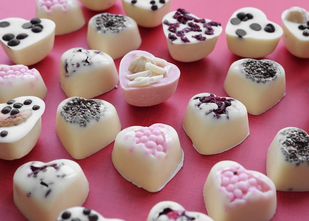 Chocolate in the shape of hearts closeup on a pink background