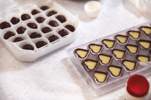 Chocolate shells full of filling of salted caramel cream lying on a table next to homemade chocolate truffles. Manufacturing of handmade chocolates