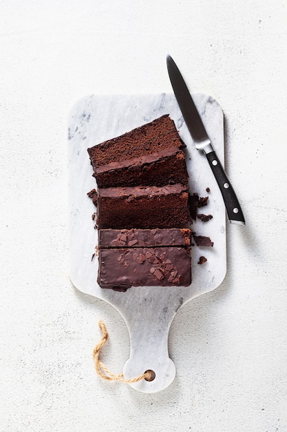 Chocolate sliced cake on a cutting board and knife