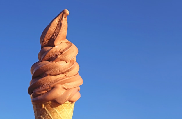 Chocolate Soft Serve Ice Cream Cone Against Sunny Vibrant Blue Sky