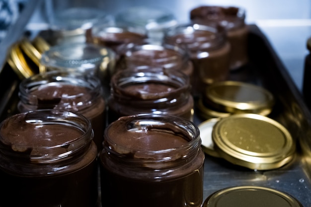 Chocolate spread in spoon with jar on dark background