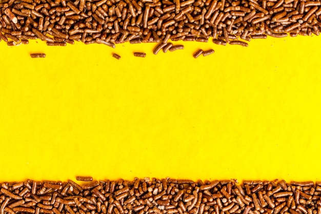 Chocolate sprinkles on yellow surface.