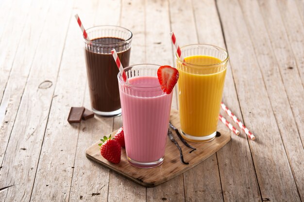 Chocolate, strawberry and vanilla milkshakes on rustic wooden table