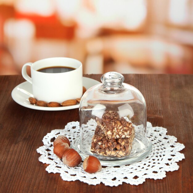 Chocolate sweets under glass cover and hot drink on bright background