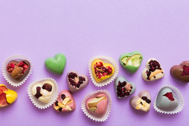 写真 チョコレート・スイーツは心の形で色の背景に果物とナッツが付いておりテキスト・ホリデー・コンセプトのスペースを備えたトップビューです