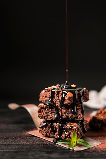 Chocolate syrup poured over tower of chocolate nut brownies on tray