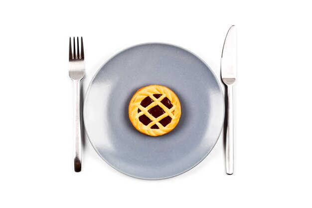 Chocolate tart on grey ceramic plate, fork and knife 