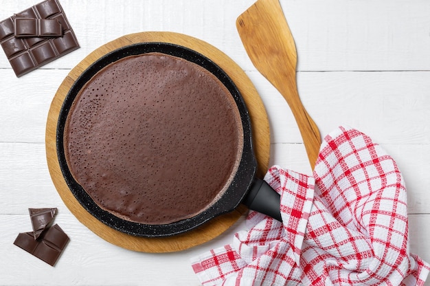 Chocolate thin pancake in a pan on a wooden stand Tasty breakfast