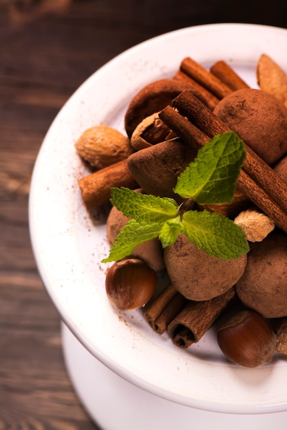 Chocolate truffle candies and assortment of nuts on white stand