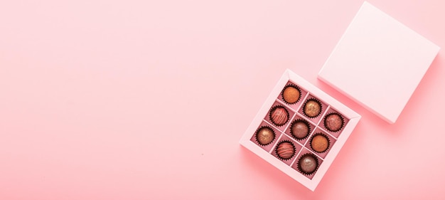 Chocolate truffle candies in a box pink background Gifts festive food love concept Horizontal frame copy space