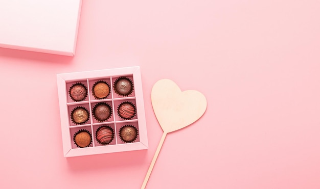 Chocolate truffle candies in a box pink background Gifts festive food love concept Horizontal frame copy space