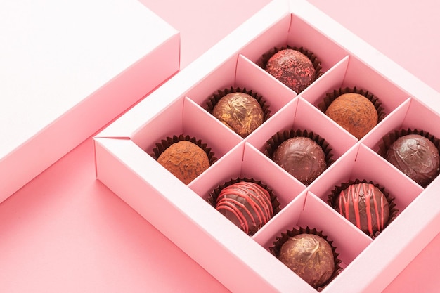 Chocolate truffle candies in a box pink background Gifts festive food love concept Horizontal frame copy space