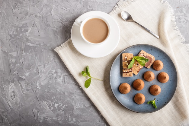 Chocolate truffle with piece of milk chocolate on blue ceramic plate. 