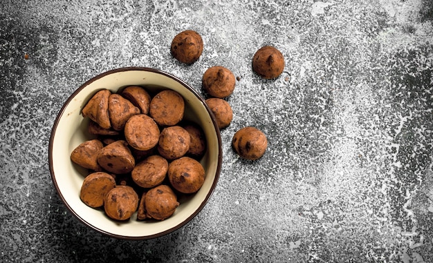 Chocolate truffles in a bowl. On a rustic table.