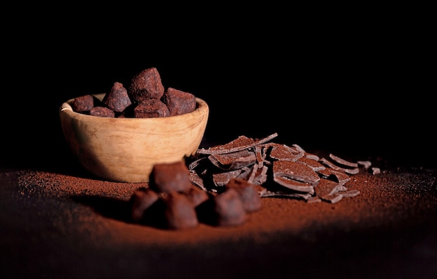 Chocolate truffles covered with cocoa powder in a wooden cup\
and a slide of milk chocolate