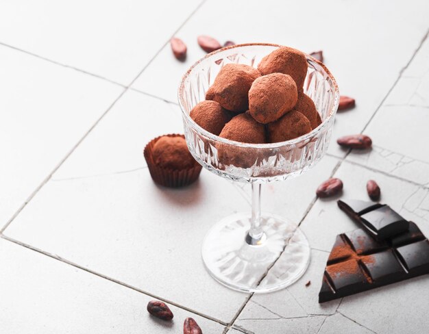 Chocolate truffles Homemade chocolate truffles with cocoa powder on glass on old cracked tile table background Tasty sweet chocolate truffles candies Valentine's Day and Mother's Day concept