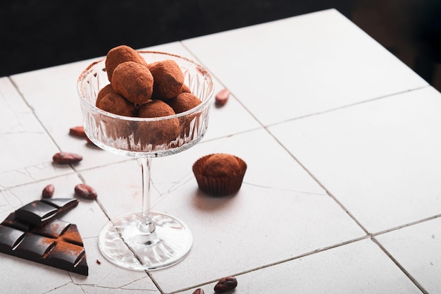 チョコレートトリュフ古いひびの入ったタイルテーブルの背景にガラスにココアパウダーと自家製チョコレートトリュフおいしい甘いチョコレートトリュフキャンディーバレンタインデーと母の日のコンセプト