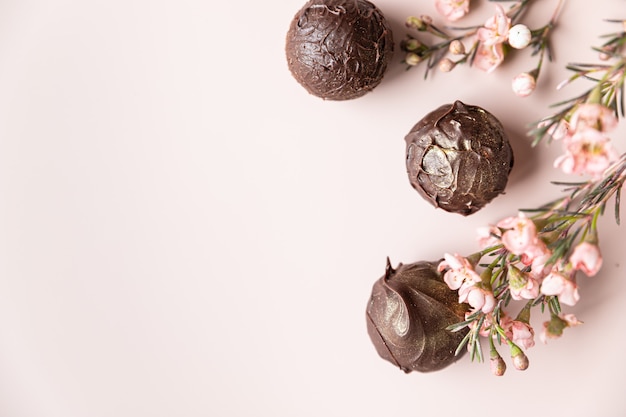 Chocolate truffles on a pink background decorated with pink flowers Minimalism