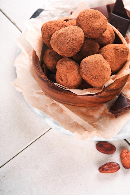 Chocolate truffles with cocoa powder in wooden dish on old\
cracked tile table background tasty sweet chocolate truffles\
candies valentine\'s day and mother\'s day concept with copy space\
top view