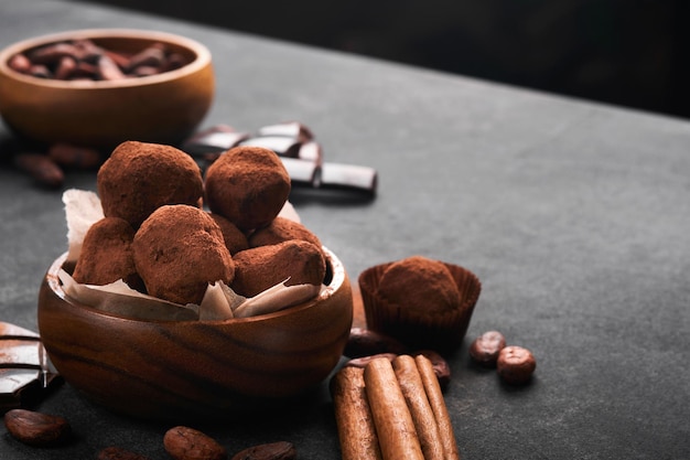Chocolate truffles with cocoa powder in wooden dish on old dark concrete table background Tasty sweet chocolate truffles candies Valentines Day and Mothers Day concept with copy space Top view