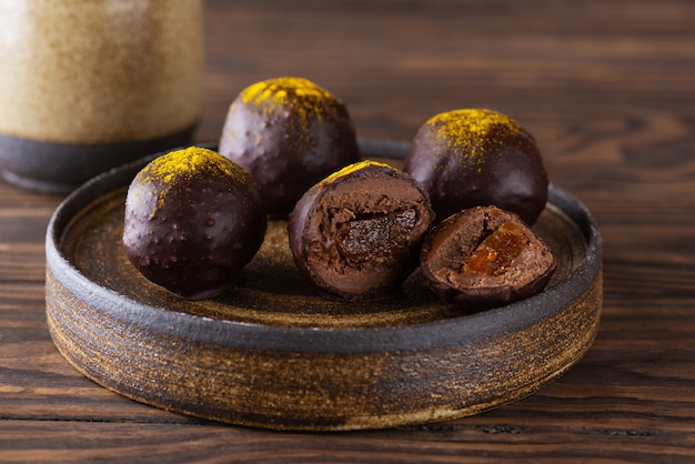 Chocolate truffles with orange filling on a brown wooden table
