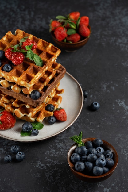 Chocolate and vanilla Belgian waffles with fresh berries on a ceramic plate