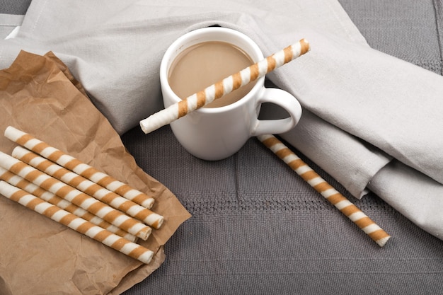 Chocolate Wafer Sticks and Cup of Coffee with Milk on Gray Background