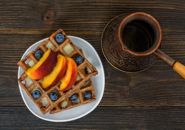 Chocolate waffles with fruits and coffee pot