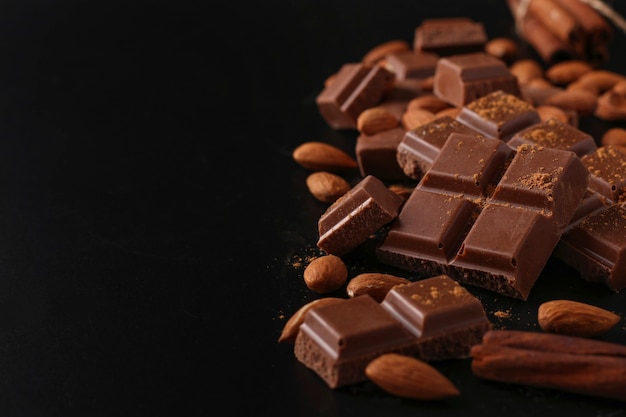 Chocolate with almonds and cinnamon on a dark table close-up, selective focus