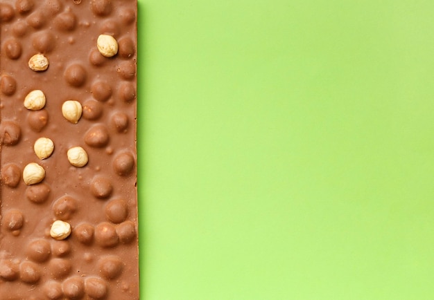 Chocolate with hazelnuts on a green background top view copy space