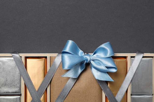 Chocolates in box with ribbon on gray background space for text