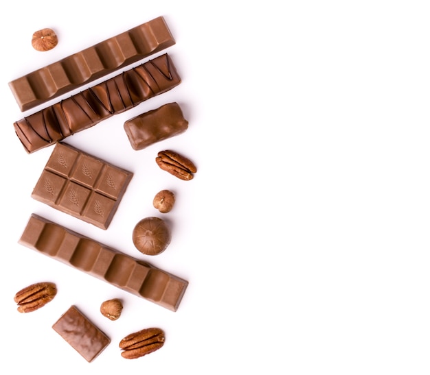 Chocolates of different shapes and pecan nut on a white, top view.