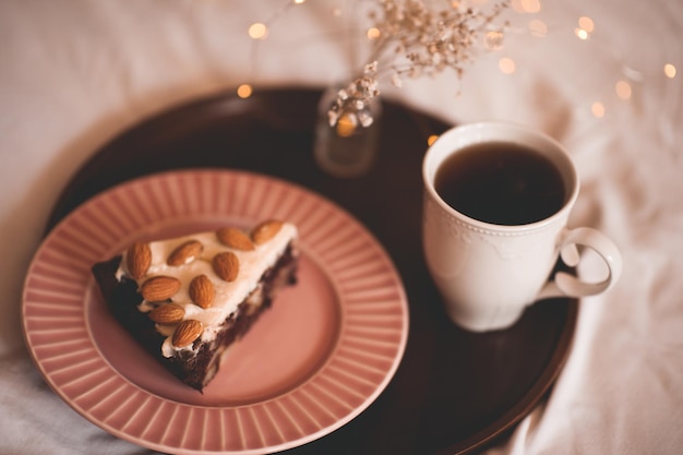 Chocolte pastry with cup of coffee on wooden tray in bed. Good morning.