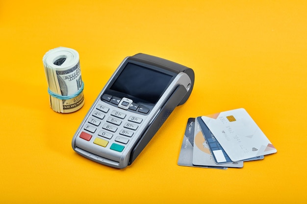 Choice among hundred dollar bills and credit cards on yellow background concept of cash vs bank