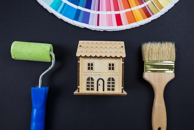 Foto scelta del colore per la pittura della casa tavolozza dei colori guida giocattolo casa in legno e spazzole su nero vista dall'alto riparazione dell'appartamento della casa