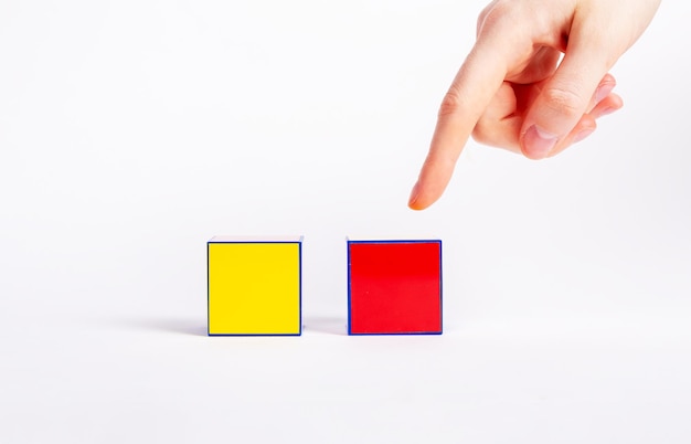 Choice concept Forefinger pointing to red cube instead of yellow one Making decision between two variants proposals