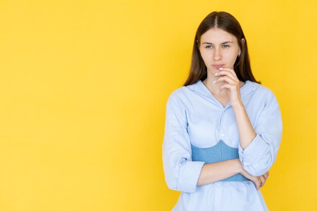 Choice problem Puzzled woman Confusion idea Thoughtful pretty lady in casual stylish look pondering holding hand on chin isolated yellow copy space