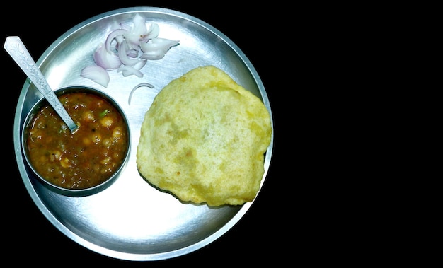 Chole Bhature 또는 병아리 완두콩 카레와 프라이드 푸리는 텍스트를 위한 빈 공간이 있는 검정 배경 위에 접시와 그릇에 제공됩니다.