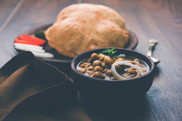 Chole Bhature или карри из нута и жареный пури подаются в терракотовой посуде на белом фоне. выборочный фокус